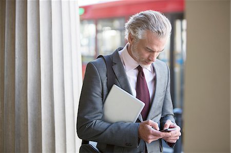 Businessman using cell phone on city street Stock Photo - Premium Royalty-Free, Code: 6113-07160652