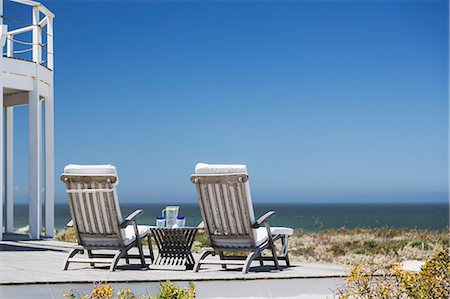 Lounge chairs on patio overlooking ocean Foto de stock - Sin royalties Premium, Código: 6113-07160795