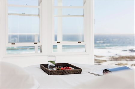 Breakfast tray and magazine on bed overlooking ocean Stock Photo - Premium Royalty-Free, Code: 6113-07160837