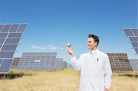 Scientist examining sphere by solar panels Stock Photo - Premium Royalty-Free, Code: 6113-07160940