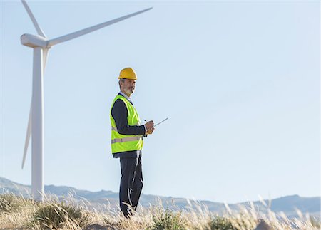 Businessman examining wind turbines in rural landscape Stock Photo - Premium Royalty-Free, Code: 6113-07160957