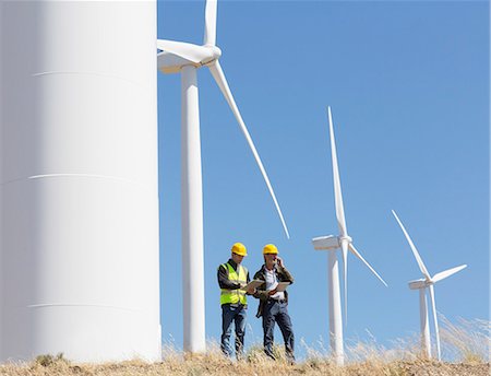 Workers talking by wind turbines in rural landscape Stock Photo - Premium Royalty-Free, Code: 6113-07160931
