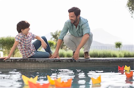 Father and son watching origami boats in swimming pool Photographie de stock - Premium Libres de Droits, Code: 6113-07241996