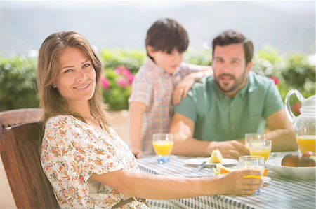 succo d'arancia - Woman smiling at patio table Fotografie stock - Premium Royalty-Free, Codice: 6113-07242084
