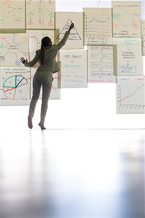 Businesswoman writing on paper on glass wall Stock Photo - Premium Royalty-Free, Code: 6113-07242177