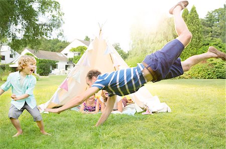 Family playing outside teepee in backyard Photographie de stock - Premium Libres de Droits, Code: 6113-07242296