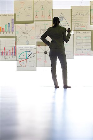 Businesswoman viewing charts and graphs on office wall Stock Photo - Premium Royalty-Free, Code: 6113-07242206