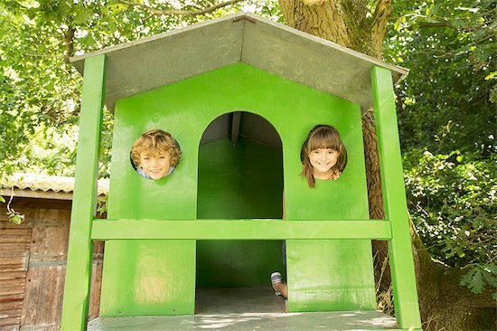 Children peeking through windows of treehouse Stock Photo - Premium Royalty-Free, Image code: 6113-07242343