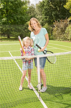 Mother and daughter smiling on grass tennis court Stock Photo - Premium Royalty-Free, Code: 6113-07242354