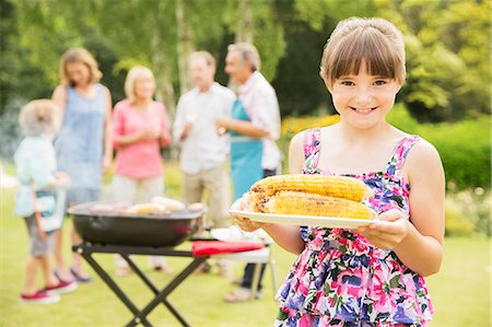 father child son grill - Smiling girl holding grilled corn in backyard Stock Photo - Premium Royalty-Free, Code: 6113-07242374