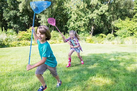 Boy and girl running with butterfly nets in grass Stock Photo - Premium Royalty-Free, Code: 6113-07242312