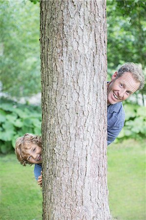 picture of a man peeking - Father and son peering from behind tree Stock Photo - Premium Royalty-Free, Code: 6113-07242441