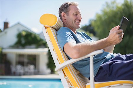 reading a tablet - Man reading in lounge chair at poolside Stock Photo - Premium Royalty-Free, Code: 6113-07242479