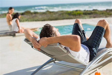 pool side - Man relaxing in lounge chair at poolside Stock Photo - Premium Royalty-Free, Code: 6113-07242493