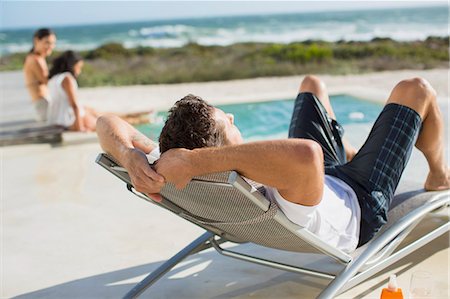 family in pool - Man relaxing in lounge chair at poolside Photographie de stock - Premium Libres de Droits, Code: 6113-07242493