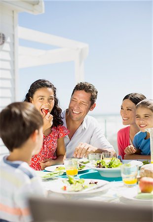 sister sits on brother laps photos - Family eating lunch on sunny patio Stock Photo - Premium Royalty-Free, Code: 6113-07242497