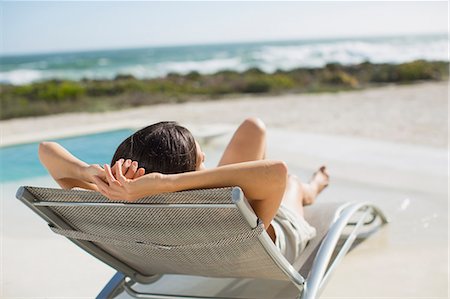Woman sunbathing on lounge chair at poolside Photographie de stock - Premium Libres de Droits, Code: 6113-07242499