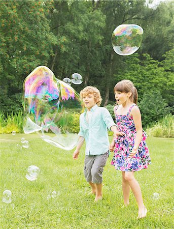 sisters playing in grass - Children playing with bubbles in backyard Stock Photo - Premium Royalty-Free, Code: 6113-07242411
