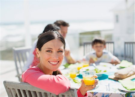 simsearch:6113-07242515,k - Woman drinking orange juice at table on sunny patio Stock Photo - Premium Royalty-Free, Code: 6113-07242541