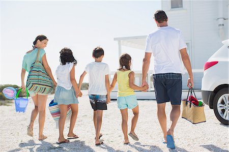 sibling - Family holding hands and carrying beach gear in sunny driveway Stock Photo - Premium Royalty-Free, Code: 6113-07242547