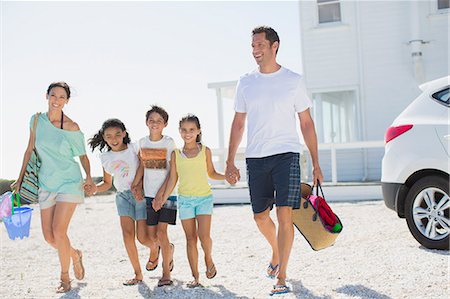 Family holding hands and walking with beach gear in sunny driveway Foto de stock - Sin royalties Premium, Código: 6113-07242554