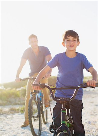 portrait images of happy kids - Father and son riding bicycles on sunny beach Stock Photo - Premium Royalty-Free, Code: 6113-07242572