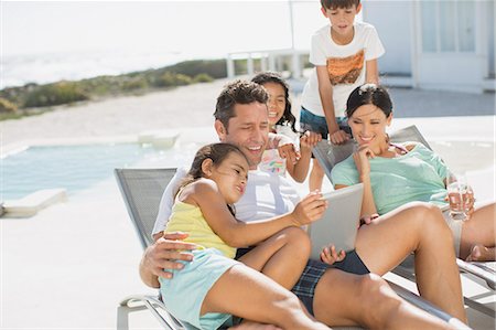 father son reading - Family using digital tablet on lounge chair at poolside Stock Photo - Premium Royalty-Free, Code: 6113-07242508