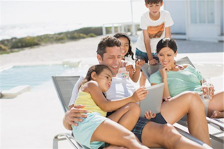 father holding son in pool - Family using digital tablet on lounge chair at poolside Stock Photo - Premium Royalty-Free, Code: 6113-07242508