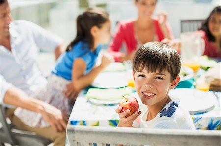 simsearch:649-07238342,k - Boy eating fruit with family at table on sunny patio Stock Photo - Premium Royalty-Free, Code: 6113-07242518