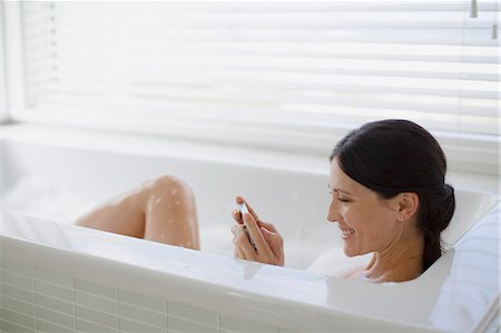 person laying in a tub - Woman using cell phone in bubble bath Stock Photo - Premium Royalty-Free, Code: 6113-07242647