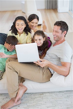 Family using laptop on sofa in living room Foto de stock - Sin royalties Premium, Código: 6113-07242613