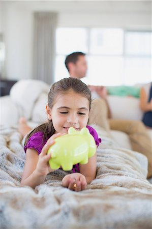 simsearch:649-03774573,k - Girl counting change in piggy bank on sofa in living room Photographie de stock - Premium Libres de Droits, Code: 6113-07242632