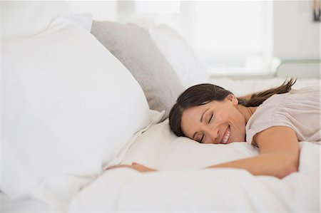 simsearch:6113-07242590,k - Smiling woman laying on bed Foto de stock - Sin royalties Premium, Código: 6113-07242634