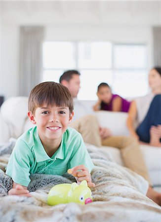 Boy counting change in piggy bank on sofa in living room Stock Photo - Premium Royalty-Free, Code: 6113-07242635