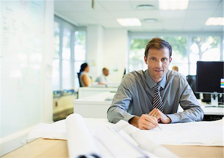 Businessman reading blueprints in office Stock Photo - Premium Royalty-Free, Code: 6113-07242746