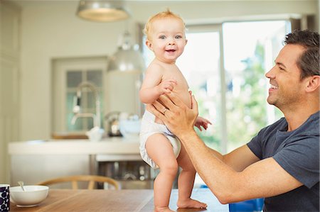 Father helping baby walk on table Stock Photo - Premium Royalty-Free, Code: 6113-07242781