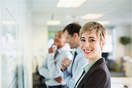 Businesswoman smiling at whiteboard in office Stock Photo - Premium Royalty-Free, Code: 6113-07242730