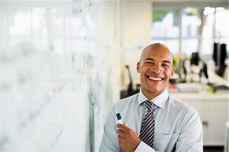 strategy - Businessman smiling at whiteboard in office Stock Photo - Premium Royalty-Free, Code: 6113-07242732