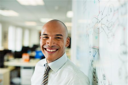 Businessman smiling at whiteboard in office Foto de stock - Sin royalties Premium, Código: 6113-07242735