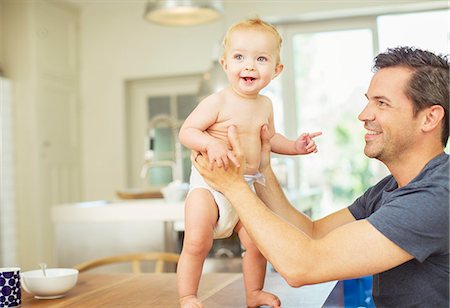 simsearch:6113-07242781,k - Father helping baby walk on table Foto de stock - Royalty Free Premium, Número: 6113-07242844