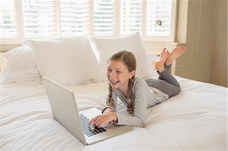 Girl using laptop on bed Foto de stock - Sin royalties Premium, Código: 6113-07242852