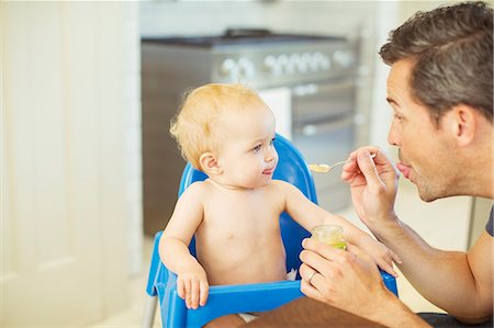 funny baby photo - Father feeding baby in high chair Stock Photo - Premium Royalty-Free, Code: 6113-07242882