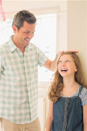 Father measuring daughter's height on wall Stock Photo - Premium Royalty-Free, Code: 6113-07242811