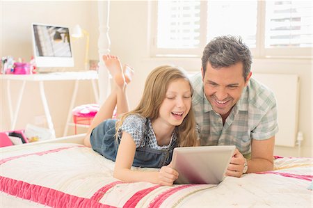 Father and daughter using digital tablet on bed Stock Photo - Premium Royalty-Free, Code: 6113-07242825