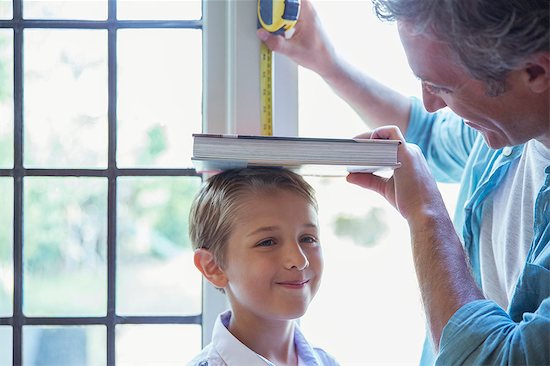 Father measuring son's height on wall Stock Photo - Premium Royalty-Free, Image code: 6113-07242973