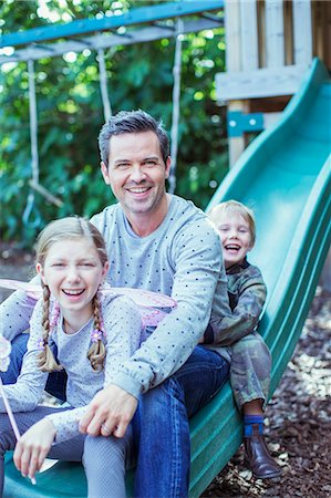 Father and children sitting on slide Stock Photo - Premium Royalty-Free, Code: 6113-07242980