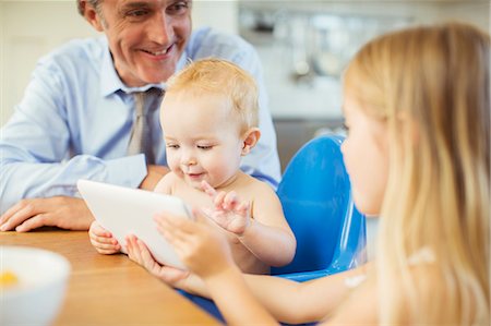 Father and children using digital tablet at table Stock Photo - Premium Royalty-Free, Code: 6113-07242901