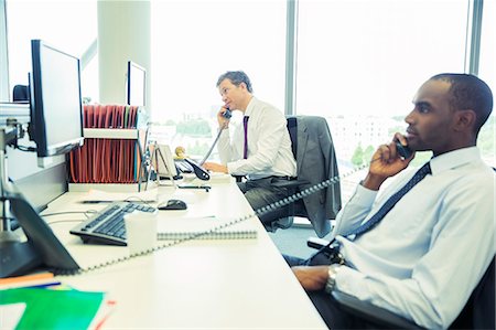 simsearch:6113-07242758,k - Businessmen talking on telephones in office Stock Photo - Premium Royalty-Free, Code: 6113-07243086