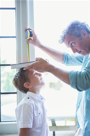 Father measuring son's height on wall Stock Photo - Premium Royalty-Free, Code: 6113-07243001