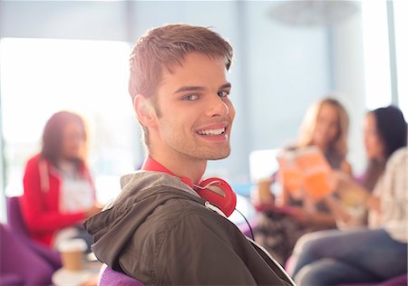 Smiling university student wearing headphones in lounge Foto de stock - Sin royalties Premium, Código: 6113-07243286